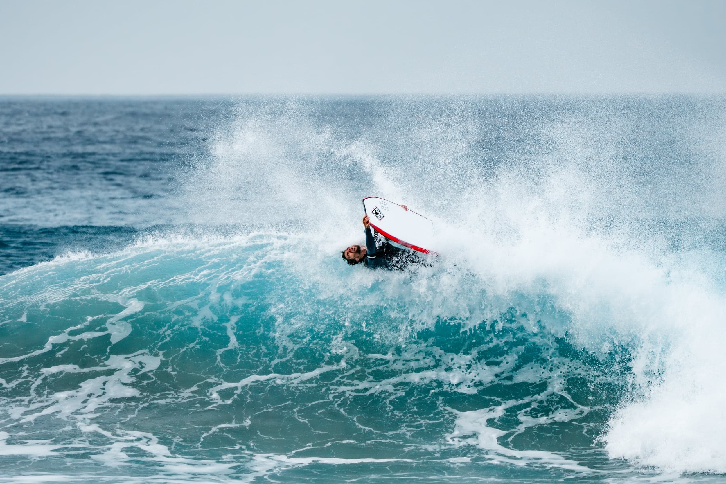 Surfer snapping a sharp off-the-lip turn, white spray exploding behind