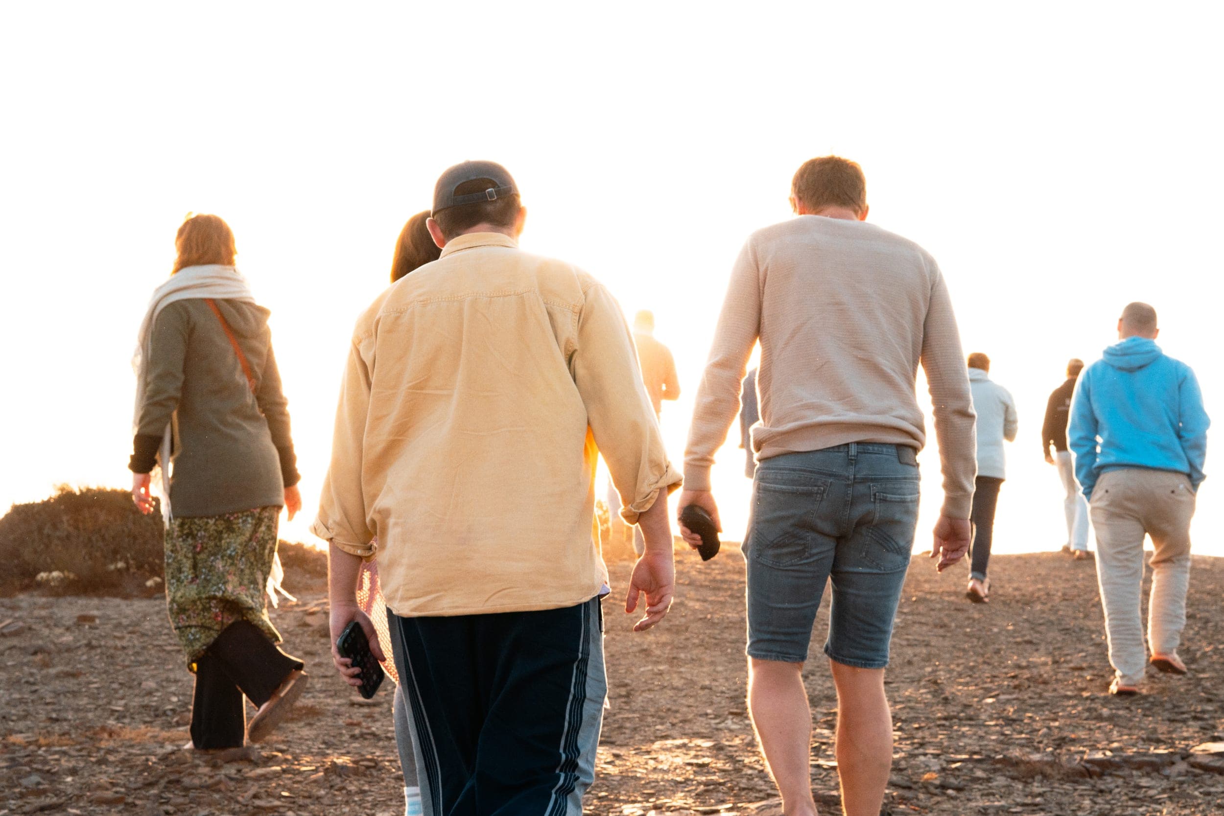 Group of retreat guests walking across rocky ground into golden sunset light
