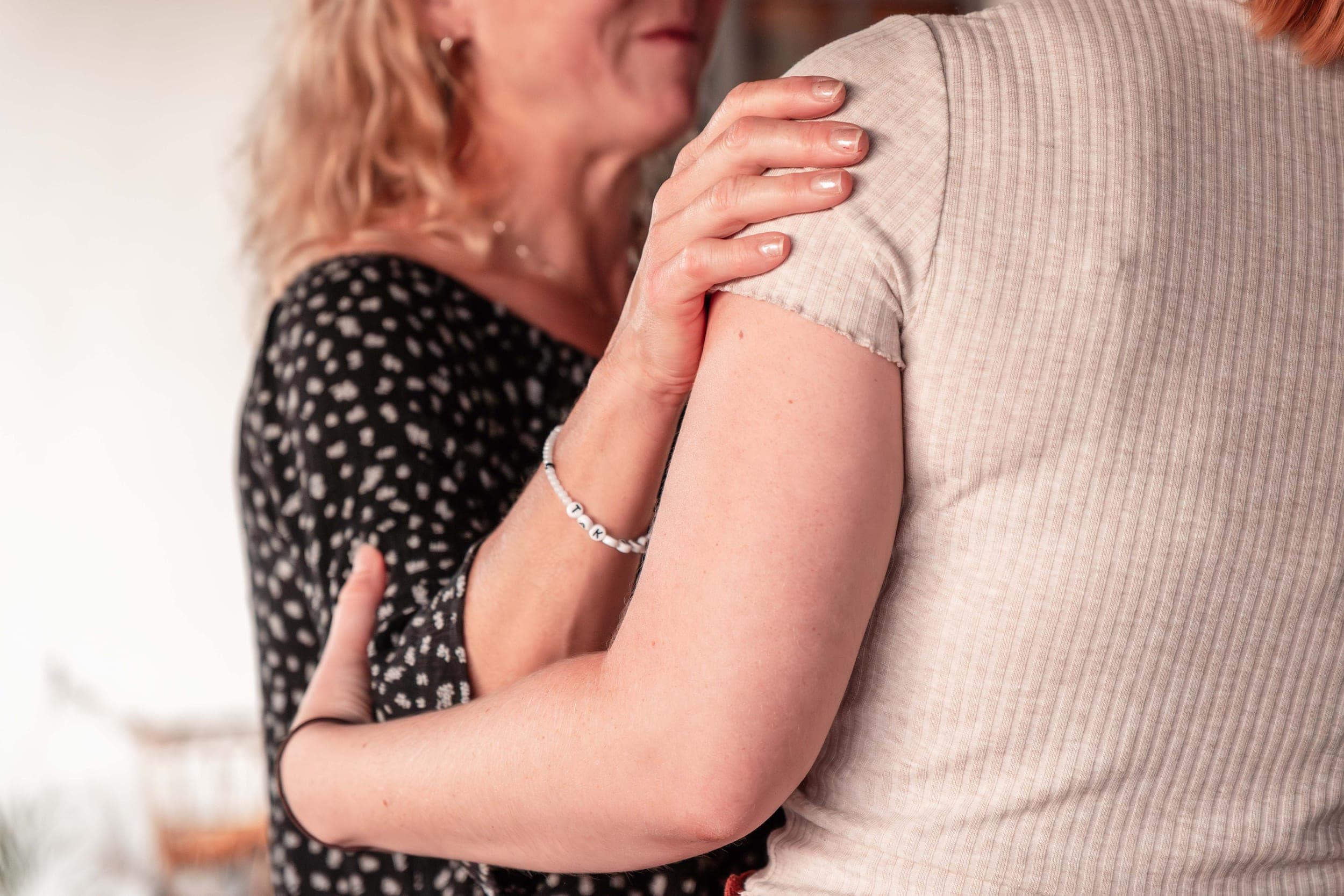 Close-up of two women embracing, one hand resting gently on the other's shoulder