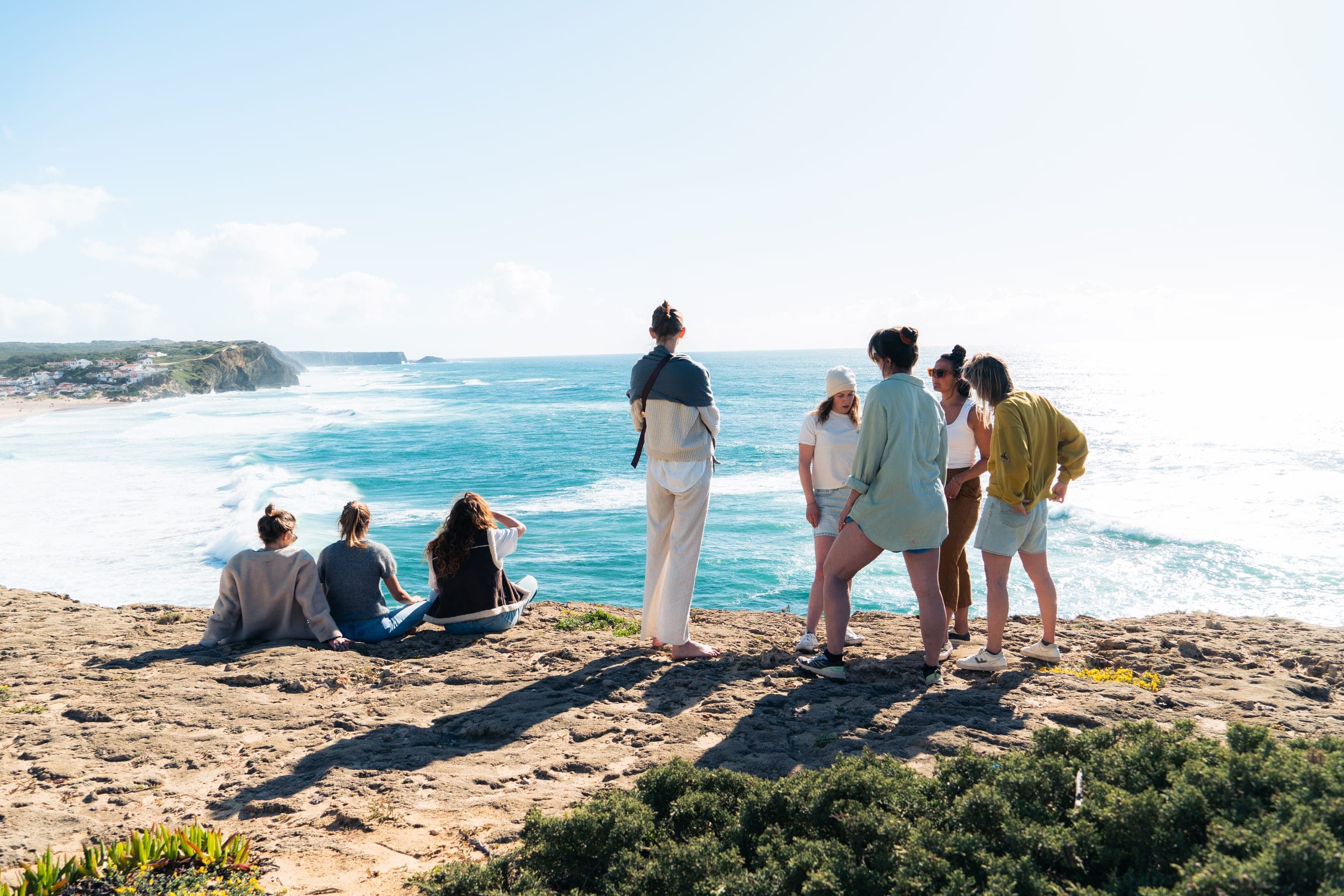 Group of women gathered on a clifftop looking out over the turquoise coastline
